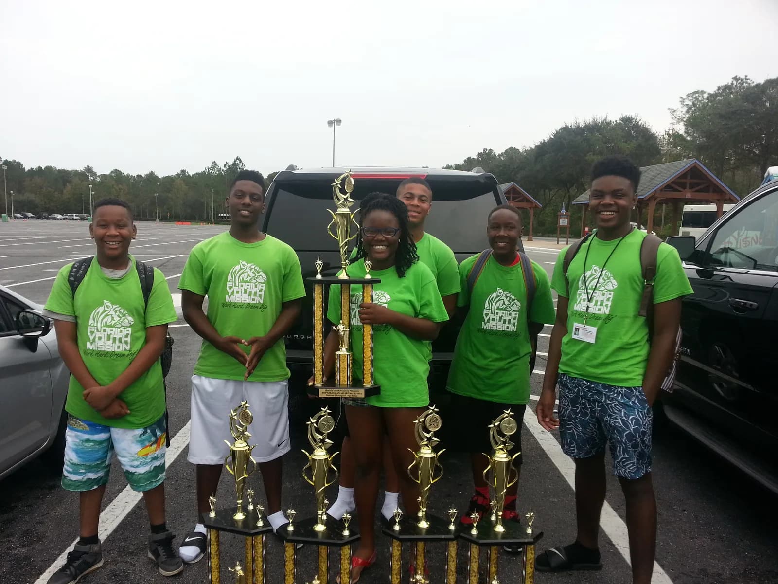 FYM youth in matching shirts holding championship trophies